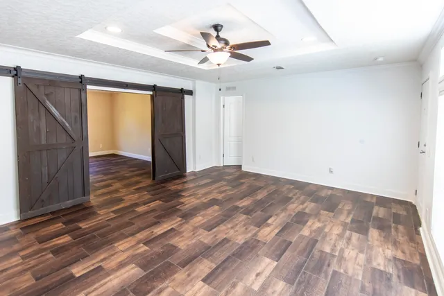 an empty room with wooden floor and ceiling fan