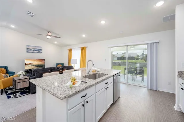 a view of a kitchen counter top space a sink a flat screen tv and a large window