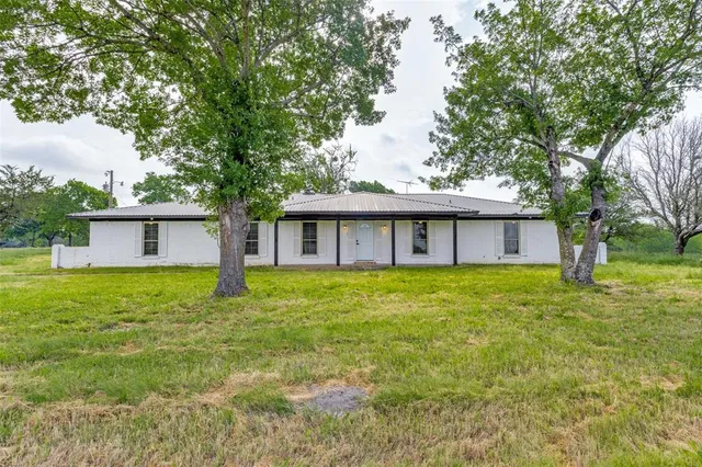 a view of a house with a yard and a large tree