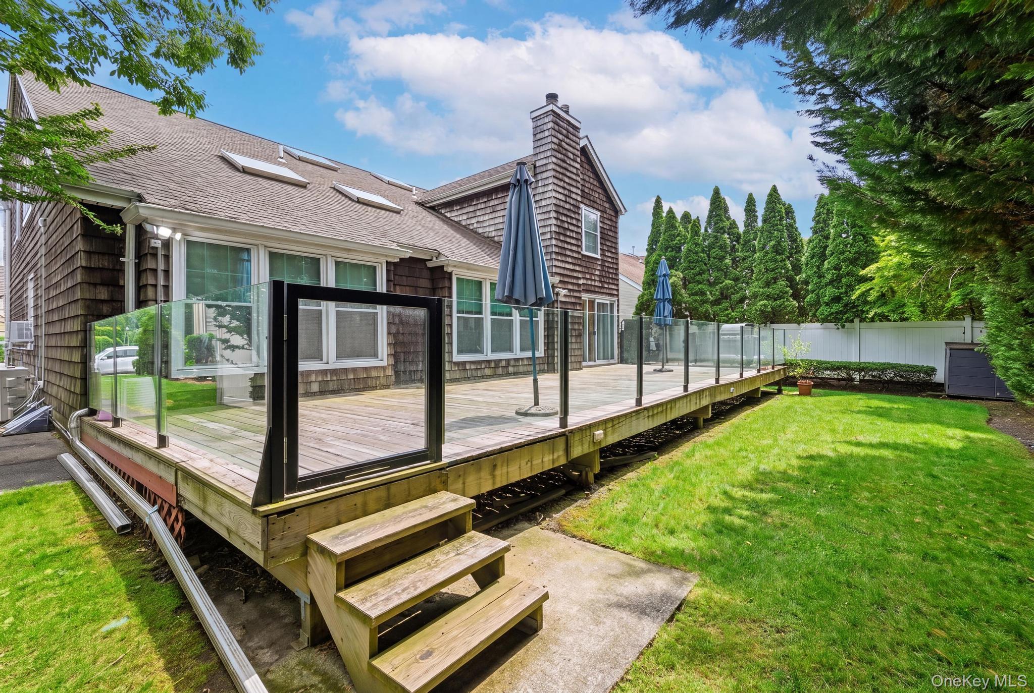 19 Sunset Road West Albertson, NY 11507 - Photo 24 of 24 A spacious deck featuring sleek tempered glass railings, creating a modern outdoor retreat with unobstructed views