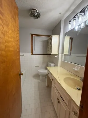 a bathroom with a granite countertop sink toilet and mirror