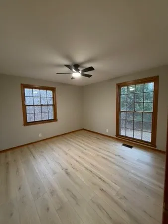 an empty room with wooden floor and windows