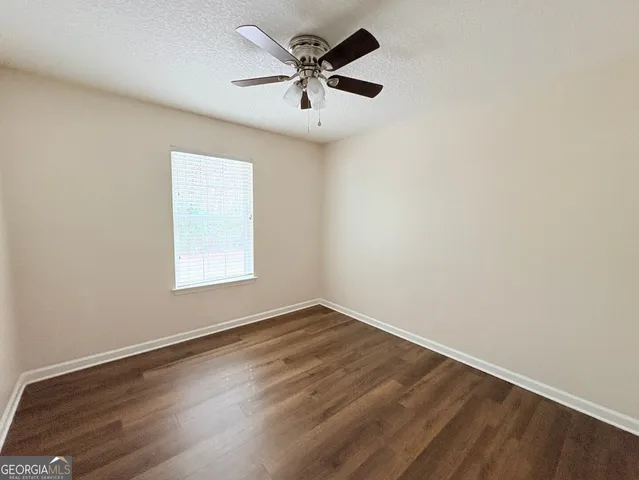 an empty room with wooden floor and ceiling fan