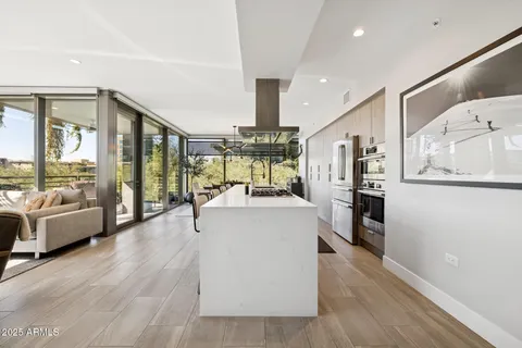 a dining hall with stainless steel appliances granite countertop a stove and chairs with wooden floor