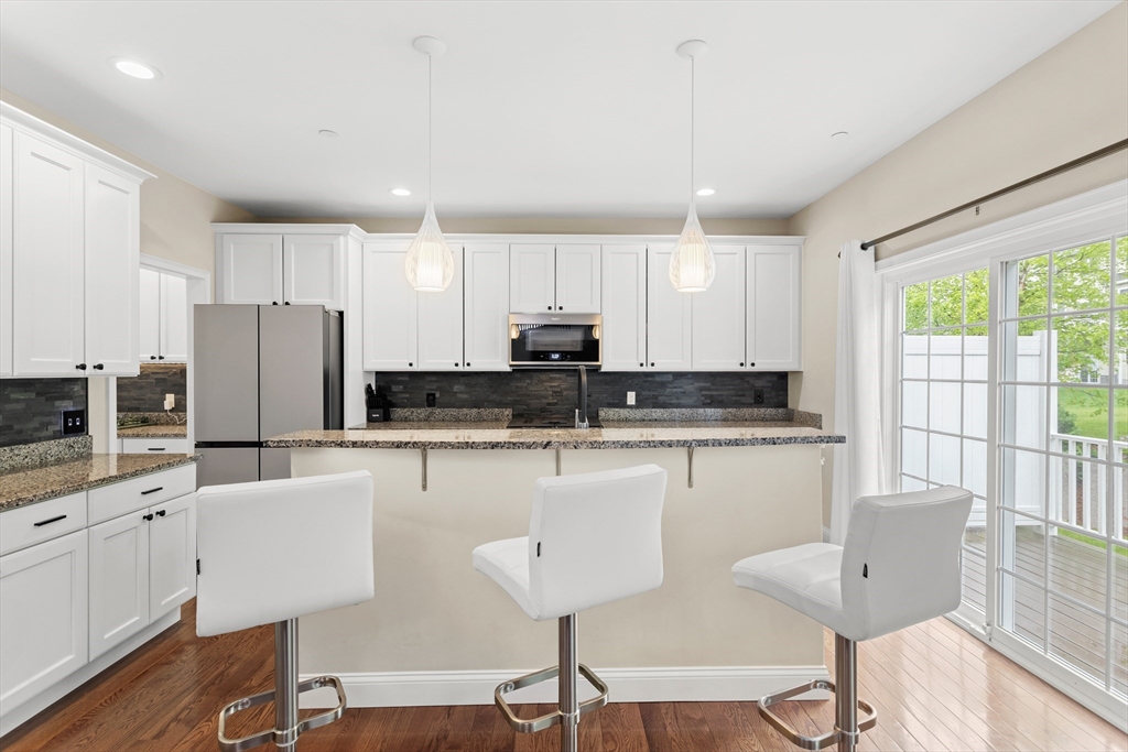 5D Manor Drive, Unit B Hooksett, NH 03106 - Photo 15 of 42 a kitchen with stainless steel appliances granite countertop a stove a sink a refrigerator white cabinets and wooden floor