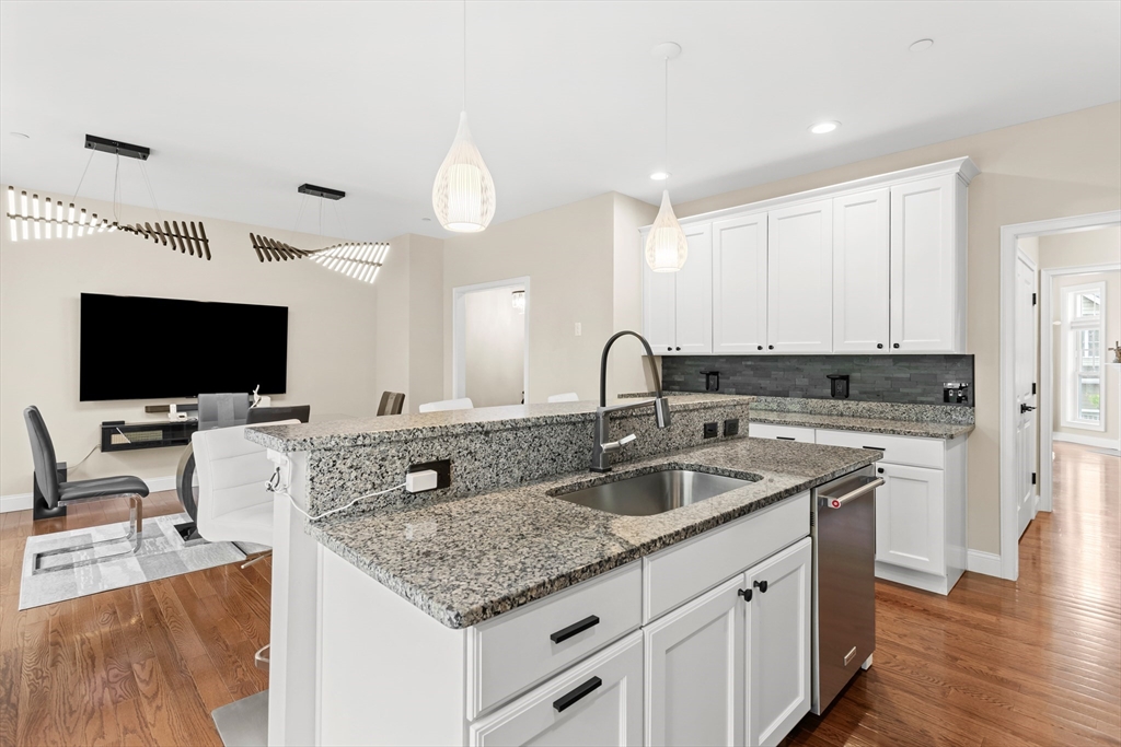 5D Manor Drive, Unit B Hooksett, NH 03106 - Photo 18 of 42 a kitchen with granite countertop a sink and a stove top oven a wooden floor