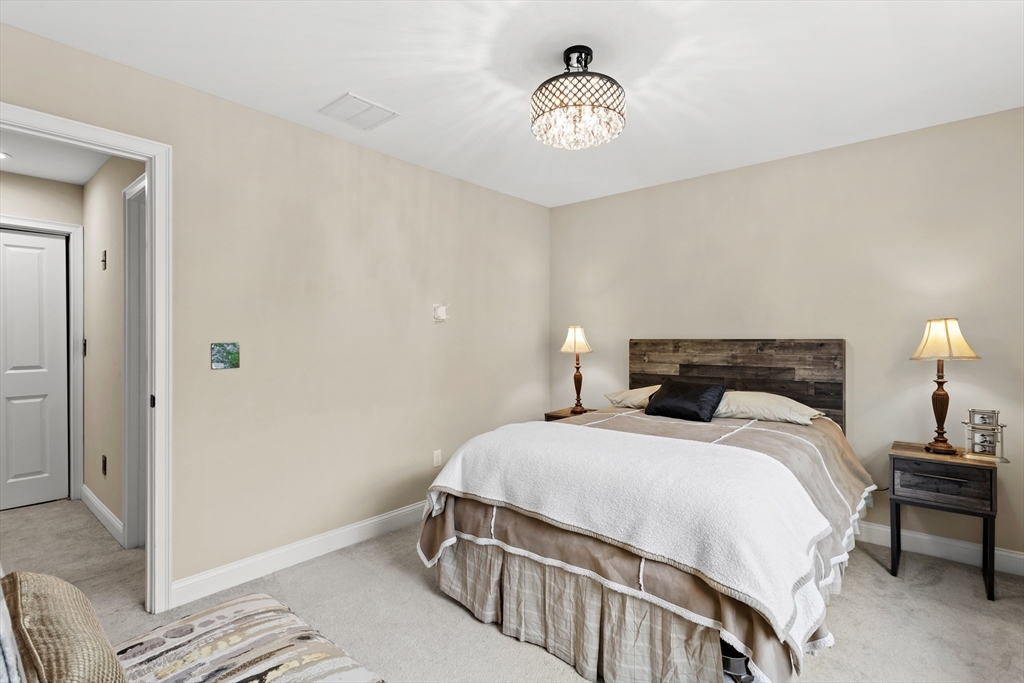 5D Manor Drive, Unit B Hooksett, NH 03106 - Photo 32 of 42 a bedroom with a bed and a chandelier