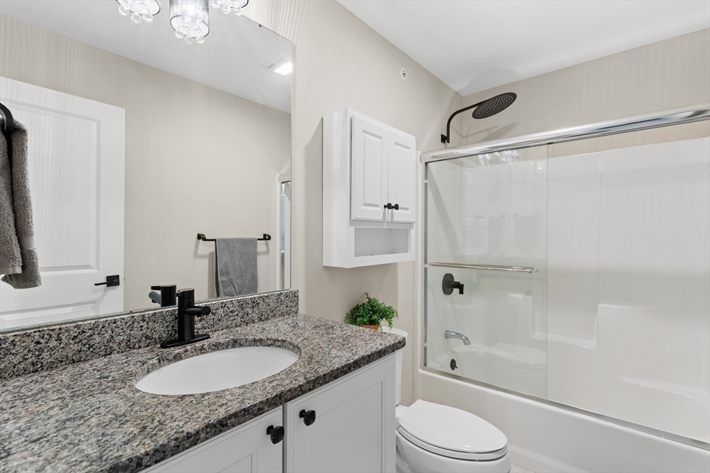 5D Manor Drive, Unit B Hooksett, NH 03106 - Photo 34 of 42 a bathroom with a granite countertop sink toilet mirror and shower