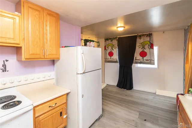a refrigerator with white cabinets and wooden floor
