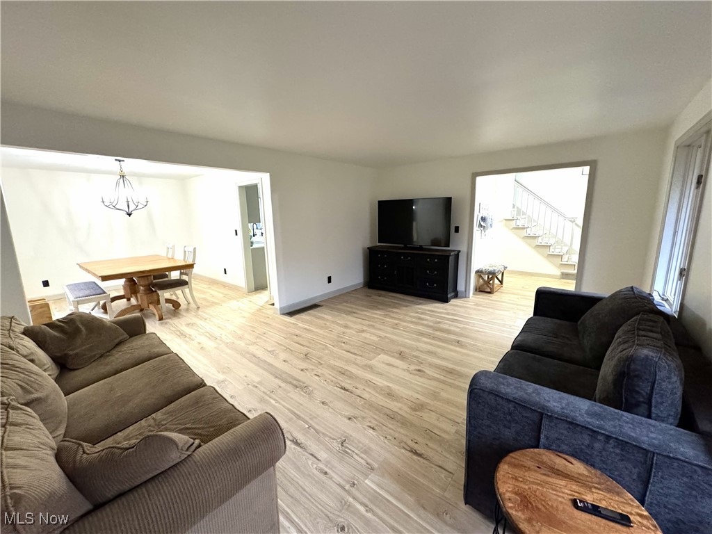 8359 Gibson Road Canfield, OH 44406 - Photo 9 of 27 Living room with light wood-style flooring, a chandelier, and stairs