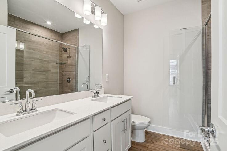 4375 Raleigh Street, Unit B1 Charlotte, NC 28213 - Photo 13 of 19 a bathroom with a double vanity sink a toilet and a mirror