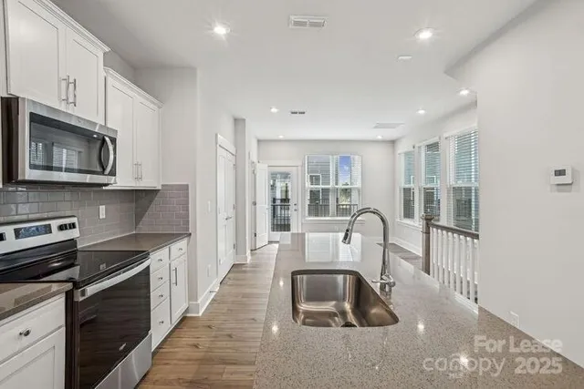 a kitchen with stainless steel appliances granite countertop a stove a sink a microwave a refrigerator and cabinets