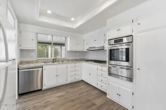 a kitchen with granite countertop white cabinets and stainless steel appliances