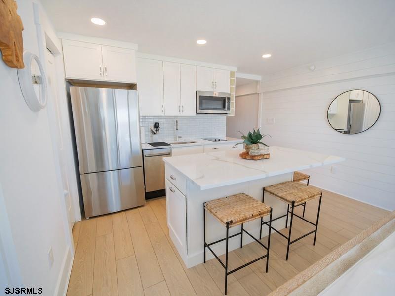 321 6th Street South, Unit 4 Brigantine, NJ 08203 - Photo 6 of 26 a kitchen with stainless steel appliances a refrigerator a stove a sink a dining table and chairs