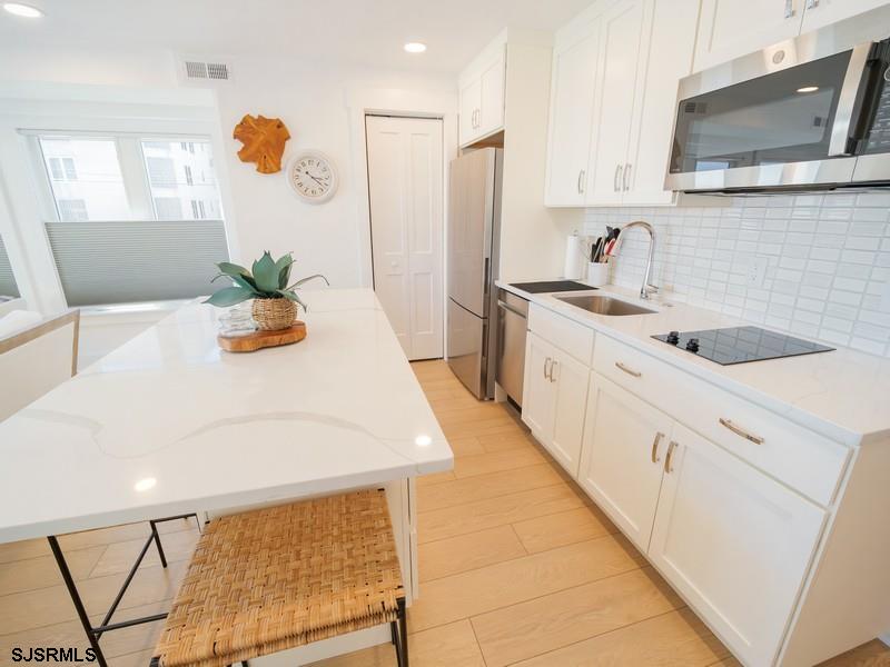321 6th Street South, Unit 4 Brigantine, NJ 08203 - Photo 7 of 26 a kitchen with stainless steel appliances a sink a stove a microwave a refrigerator and cabinets