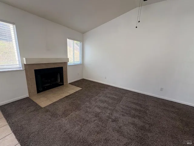 an empty room with windows and fireplace