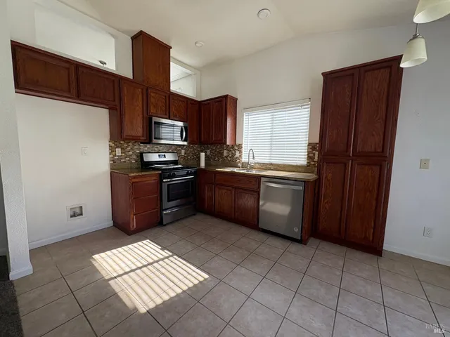 a kitchen with stainless steel appliances a sink a stove a microwave a sink a refrigerator and cabinets