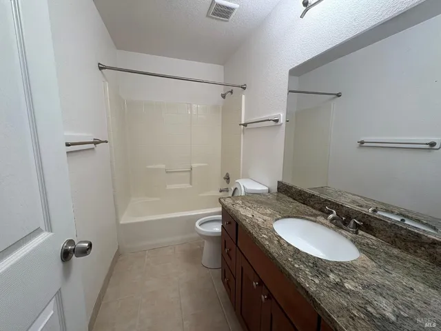 a bathroom with a granite countertop sink toilet a shower and a mirror
