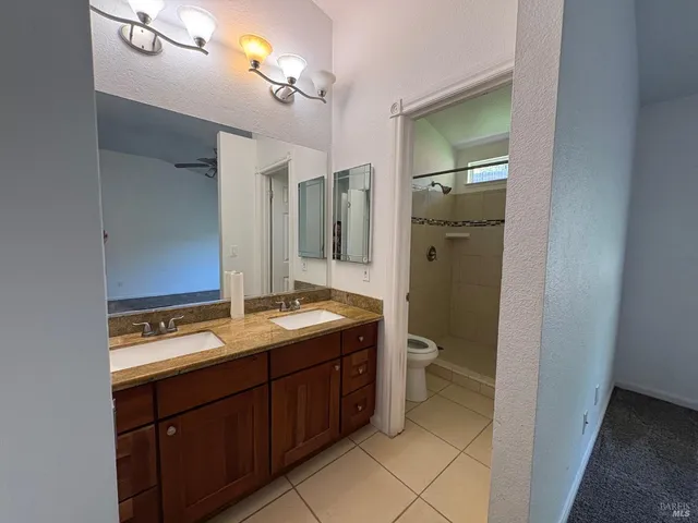 a bathroom with a granite countertop sink toilet and mirror