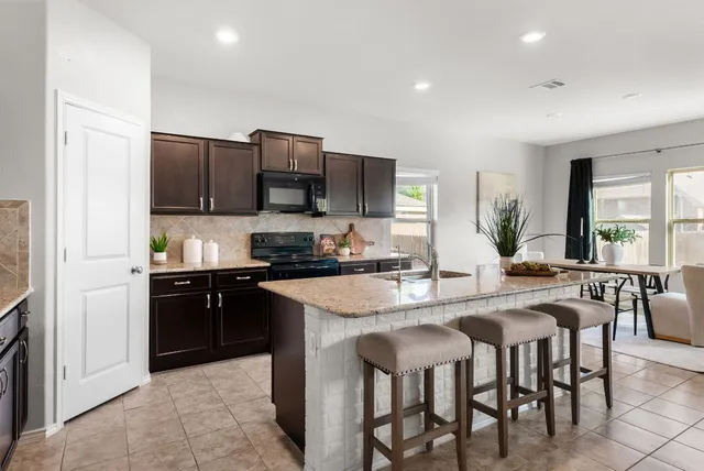 a kitchen with stainless steel appliances granite countertop a stove a sink a microwave a dining table and chairs