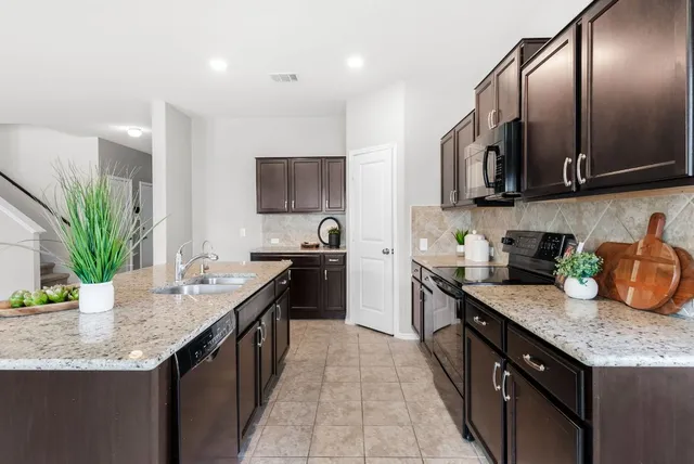 a kitchen with granite countertop stainless steel appliances a sink stove top oven and cabinets