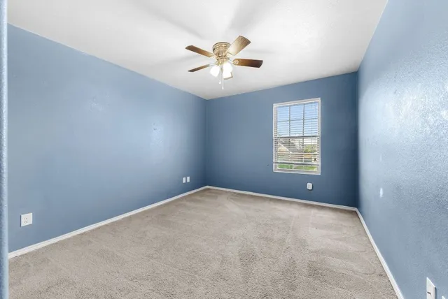an empty room with windows and fan