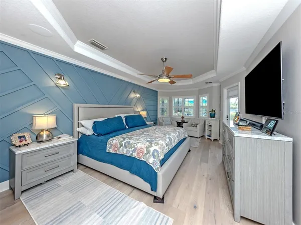 a bedroom with a large bed and a flat tv screen on dresser