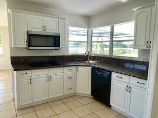22175 General Street Boca Raton, FL 33428 - Photo 12 of 32 a kitchen with white cabinets a sink and a stove with wooden floor