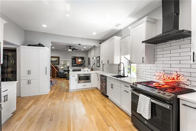 a kitchen with stainless steel appliances granite countertop a stove top oven a sink dishwasher and a refrigerator with wooden floor