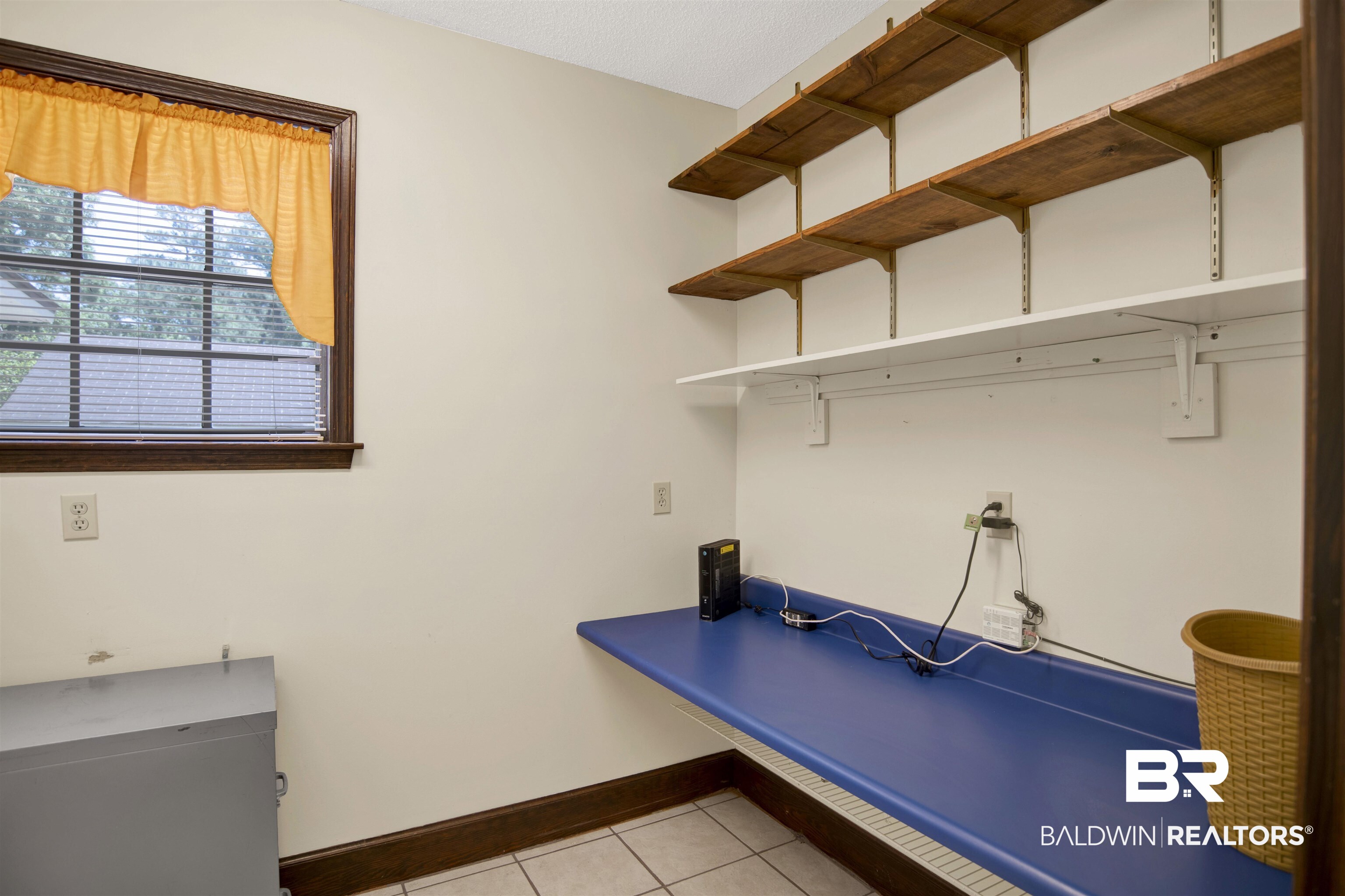 30888 Cemetery Road Daphne, AL 36527 - Photo 35 of 36 Utility room featuring a window with blinds, a built-in blue countertop, and multiple wall-mounted shelving units