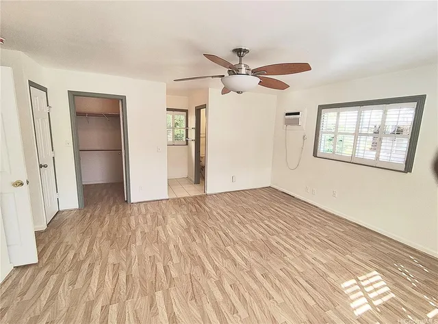 a view of empty room with wooden floor and fan