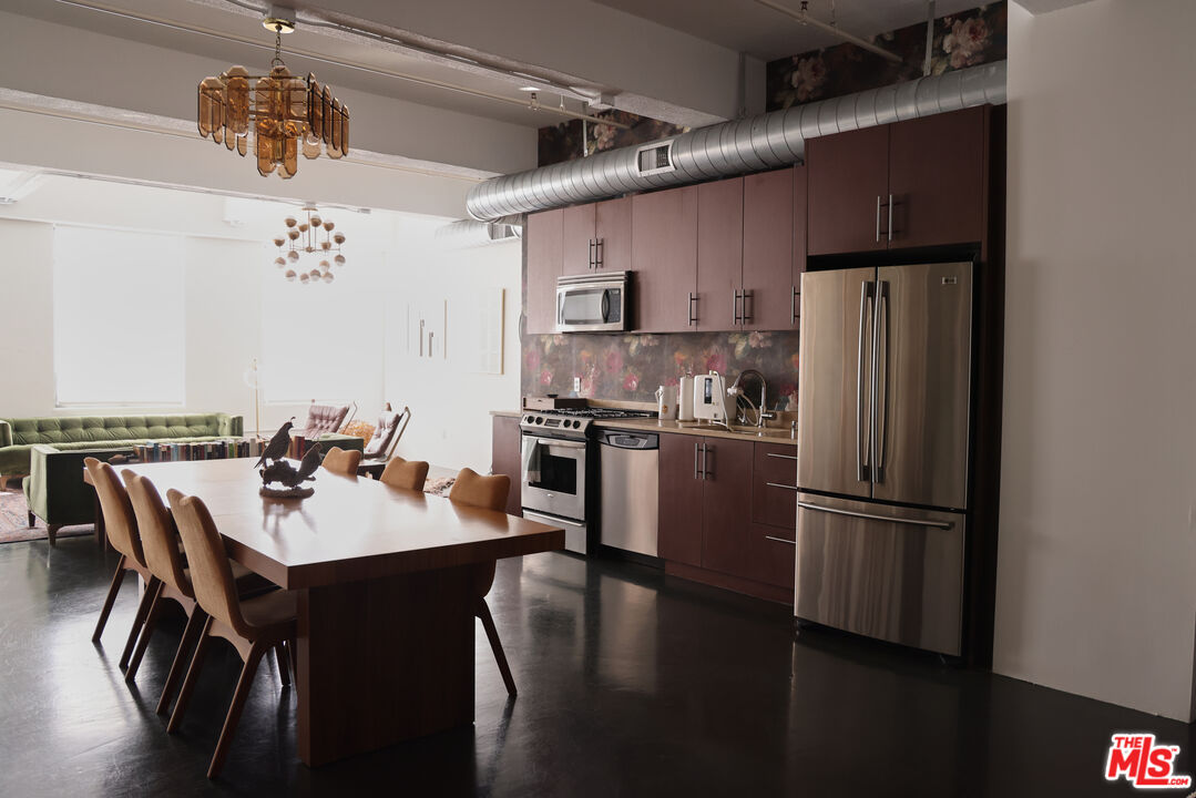849 South Broadway, Unit 906 Los Angeles, CA 90014 - Photo 18 of 65 a kitchen with stainless steel appliances granite countertop a refrigerator a sink dishwasher a stove and a dining table with wooden floor