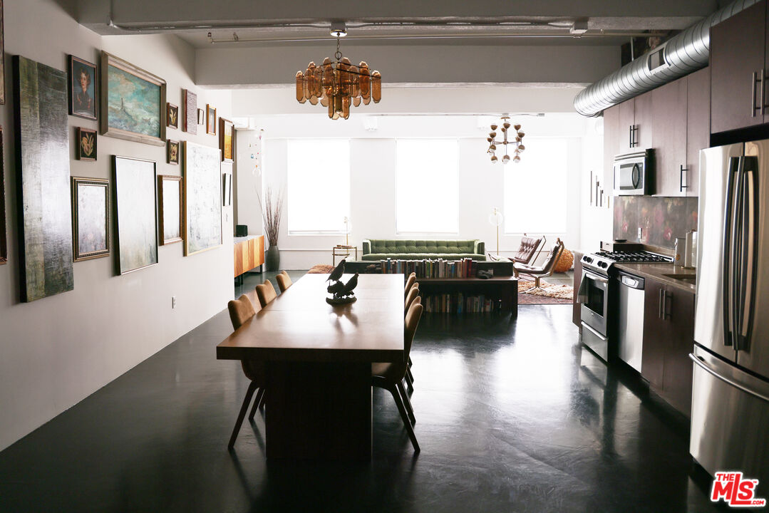 849 South Broadway, Unit 906 Los Angeles, CA 90014 - Photo 19 of 65 a kitchen with stainless steel appliances a dining table chairs refrigerator and sink