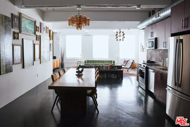 a kitchen with stainless steel appliances a dining table chairs and a refrigerator
