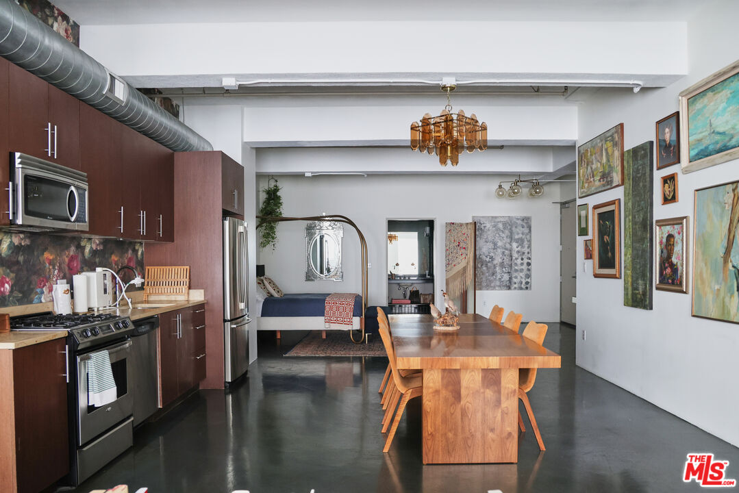 849 South Broadway, Unit 906 Los Angeles, CA 90014 - Photo 24 of 65 a dining hall with stainless steel appliances kitchen island granite countertop a stove a sink dishwasher and cabinets with wooden floor