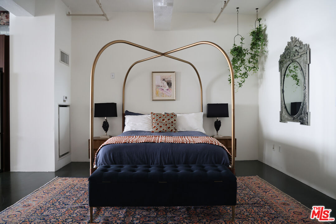 849 South Broadway, Unit 906 Los Angeles, CA 90014 - Photo 30 of 65 a spacious bedroom with a bed a dresser and potted plant