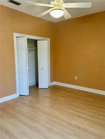an empty room with wooden floor and chandelier fan