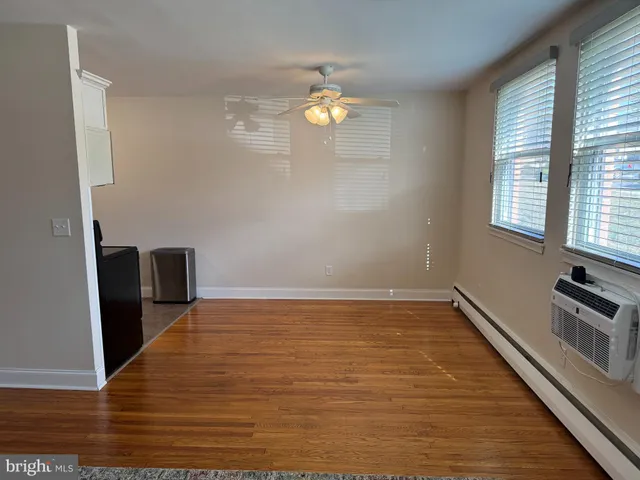 a view of empty room with wooden floor and fan