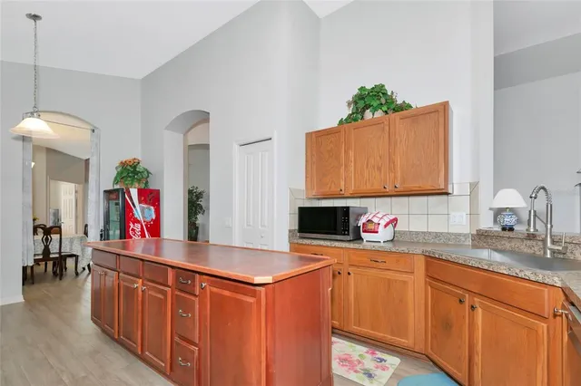 a kitchen with stainless steel appliances granite countertop a sink dishwasher and a flat tv screen next to a window