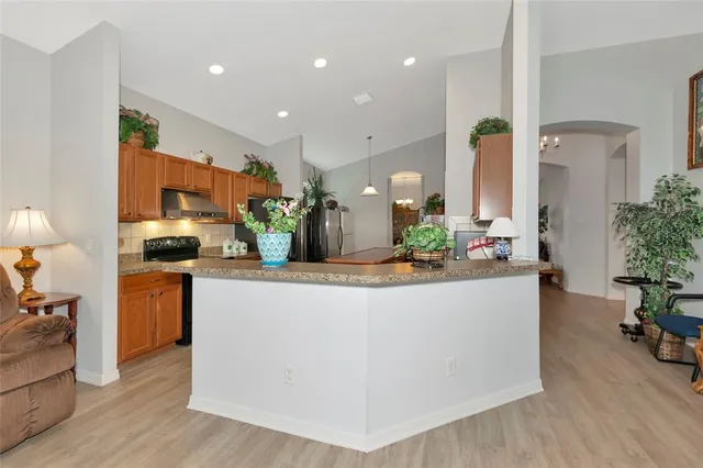 a view of living room kitchen with stainless steel appliances granite countertop furniture and wooden floor