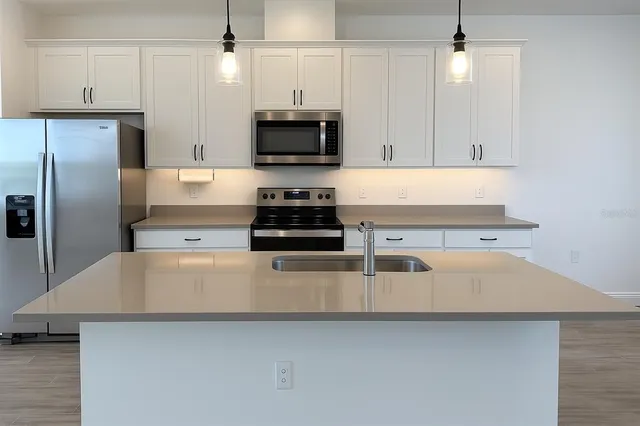 a kitchen with kitchen island a counter top space stainless steel appliances and cabinets