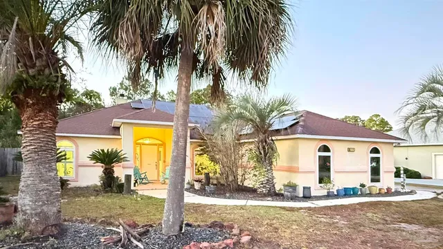 a view of a house with a yard and palm trees