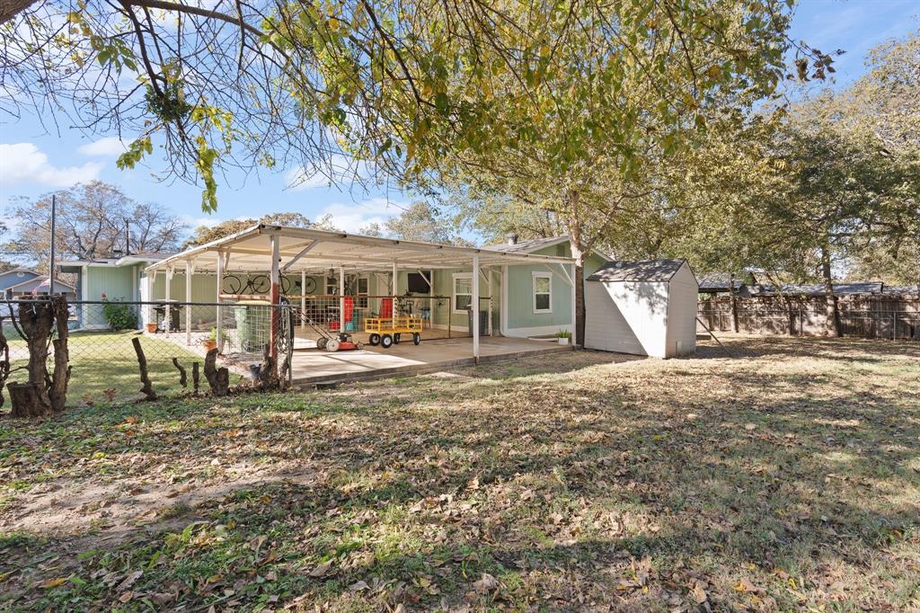 605 South 3rd Street Grandview, TX 76050 - Photo 21 of 23 Rear view of house featuring a fenced backyard, a storage shed, and a patio area