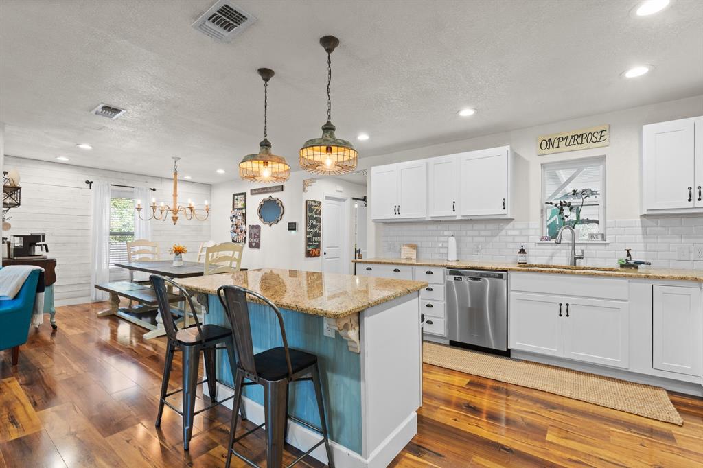 605 South 3rd Street Grandview, TX 76050 - Photo 6 of 23 Kitchen with light stone countertops, white cabinetry, hanging light fixtures, a kitchen bar, and a textured ceiling