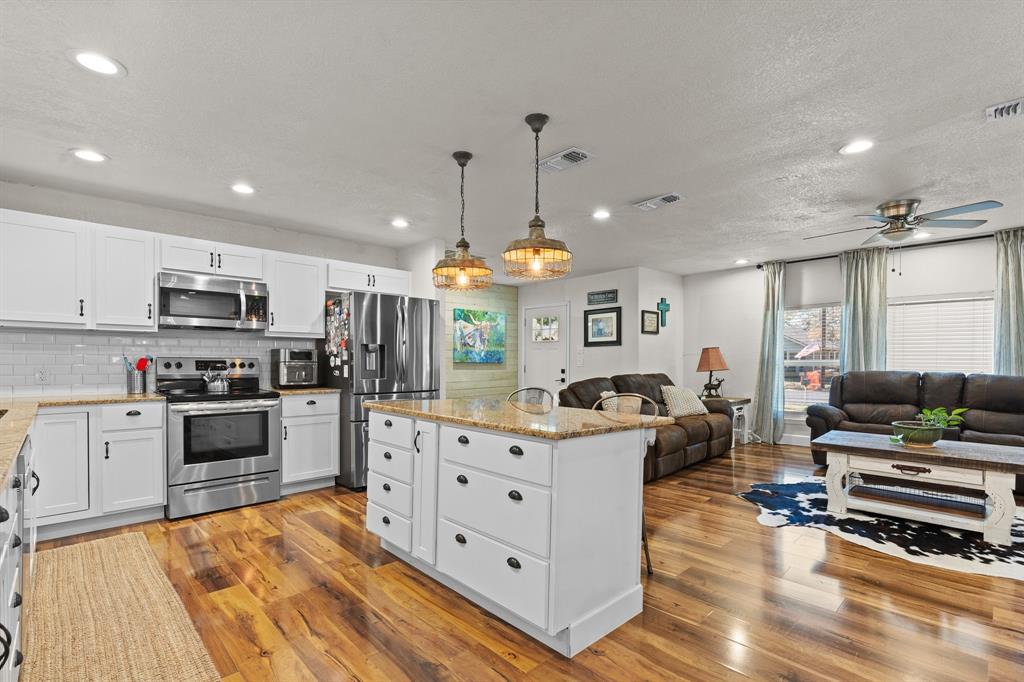 605 South 3rd Street Grandview, TX 76050 - Photo 7 of 23 Kitchen featuring white cabinetry, stainless steel appliances, hanging light fixtures, recessed lighting, and a kitchen island