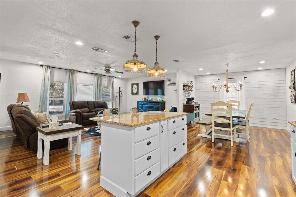 605 South 3rd Street Grandview, TX 76050 - Photo 23 of 23 Kitchen featuring light stone counters, open floor plan, pendant lighting, a center island, and a chandelier