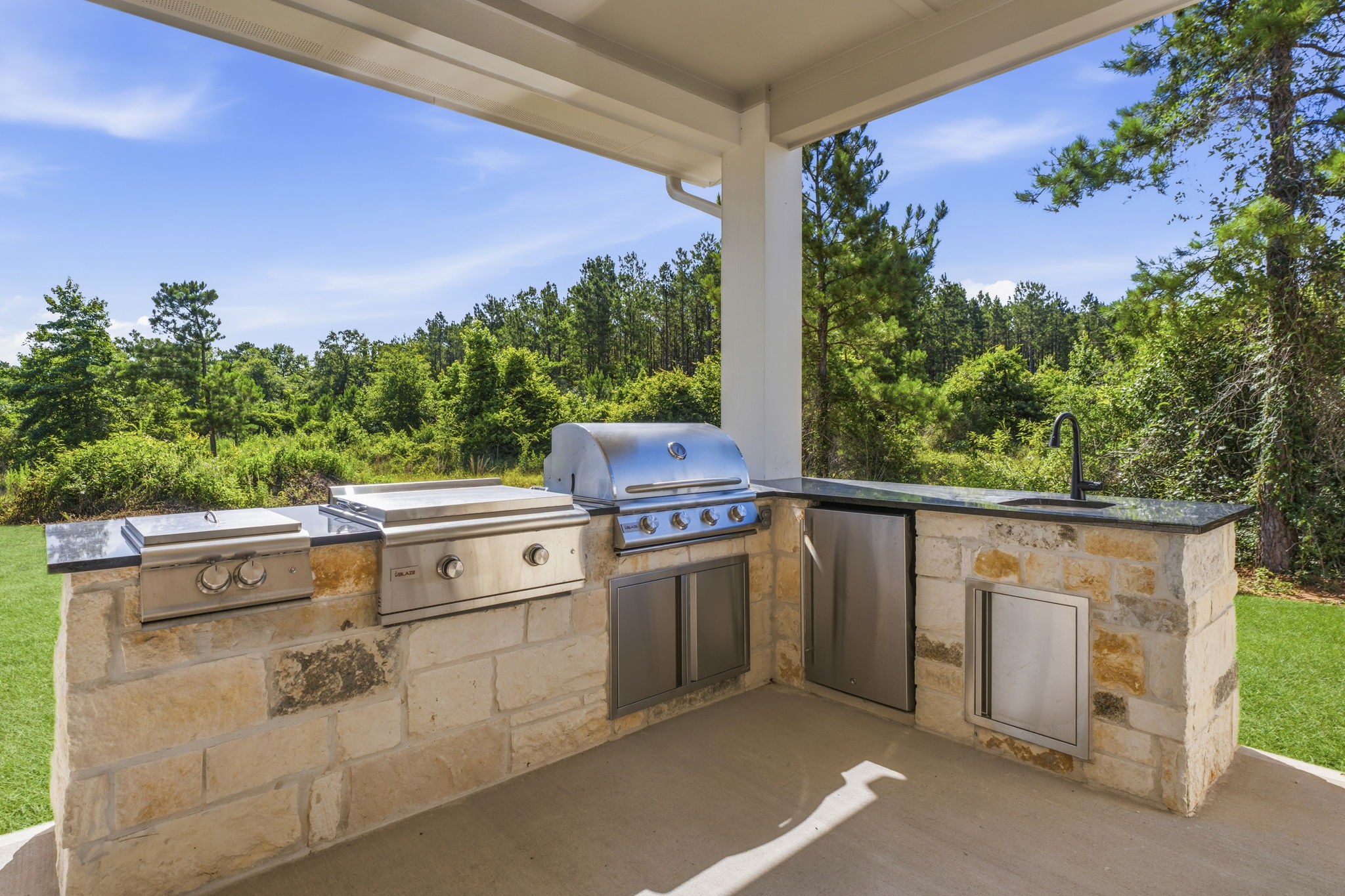 16140 Frst Ml Road Willis, TX 77378 - Photo 40 of 48 Outdoor kitchen with grill, two additional burners, griddle, refrigerator and sink