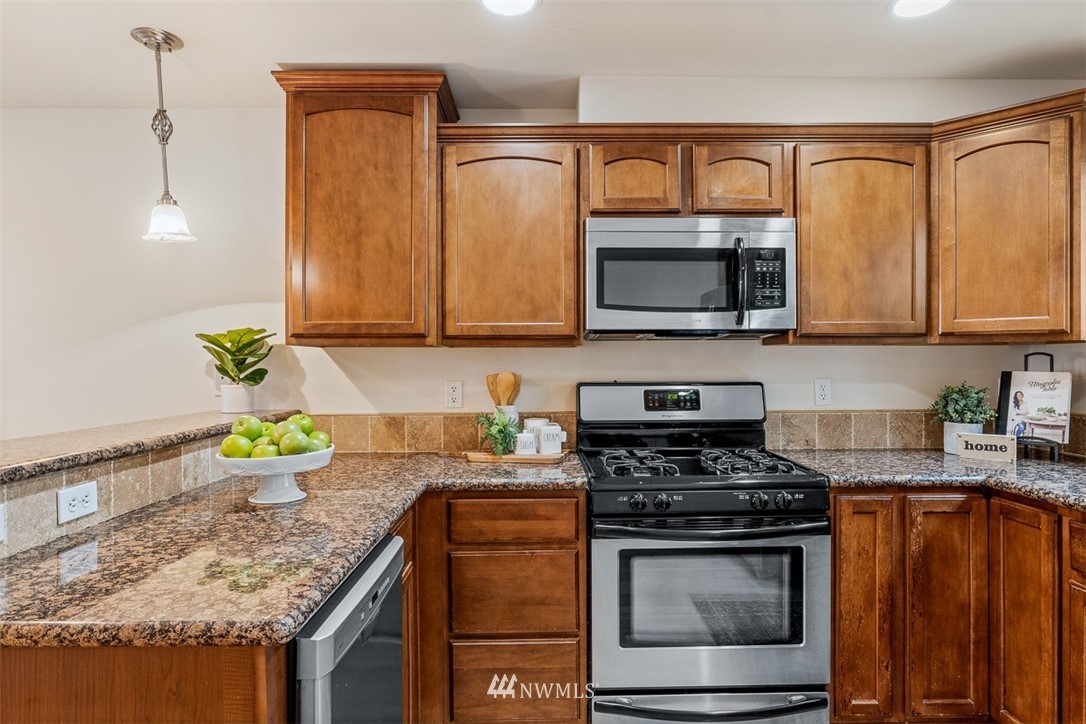 1122 North 92nd Street, Unit B Seattle, WA 98103 - Photo 11 of 32 a kitchen with stainless steel appliances granite countertop a sink stove and microwave