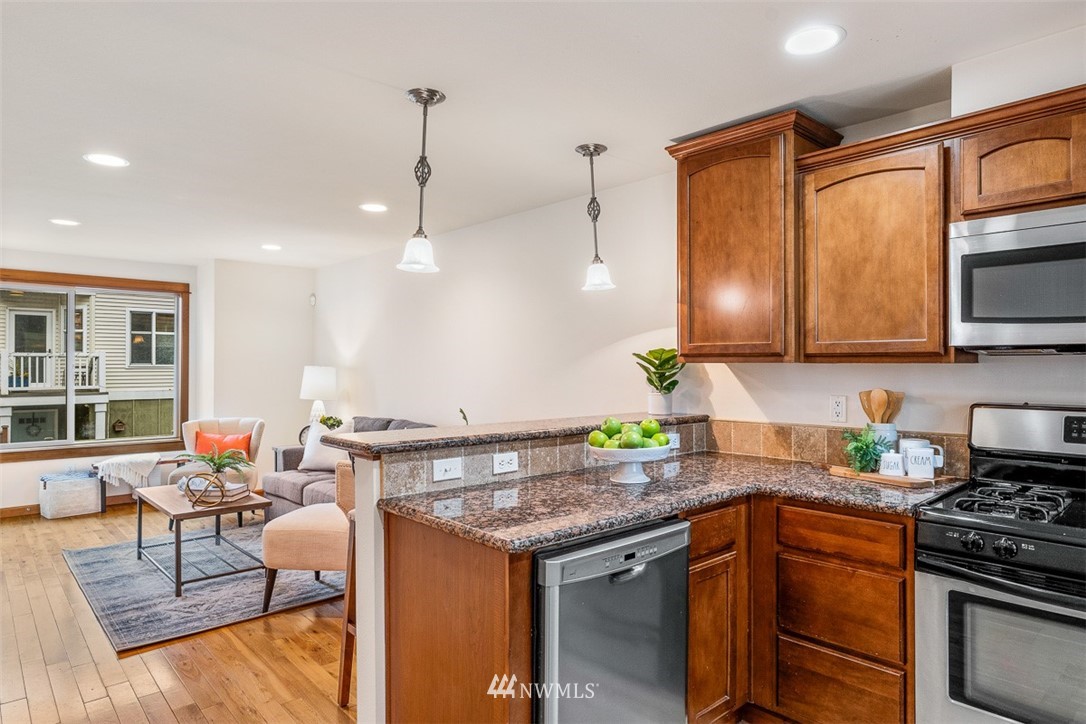 1122 North 92nd Street, Unit B Seattle, WA 98103 - Photo 13 of 32 a kitchen with stainless steel appliances granite countertop a stove a sink and a microwave
