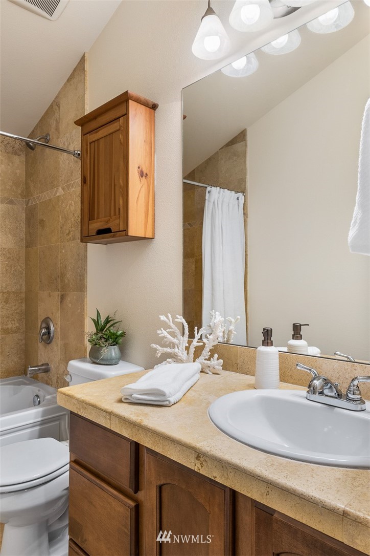 1122 North 92nd Street, Unit B Seattle, WA 98103 - Photo 24 of 32 a bathroom with a granite countertop sink a toilet and a mirror